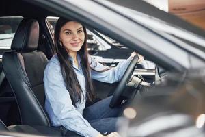 auto business, car sale, consumerism and people concept - happy woman taking car key from dealer in auto show or salon photo