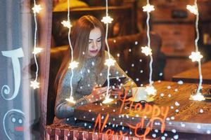 hermosa mujer joven sentada en la cafetería, bebiendo café. navidad, año nuevo, día de san valentín, concepto de vacaciones de invierno foto