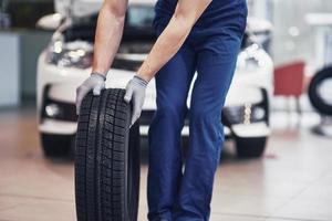 Mechanic holding a tire tire at the repair garage. replacement of winter and summer tires photo