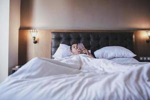 Insomnia men using smartphone  on the bed while lying under the blanket photo