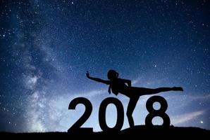 Silhouette young girl is relaxing 2018 new year background of the Milky Way galaxy on a bright star dark sky tone photo