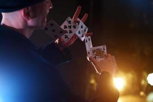 Magician showing trick with playing cards. Magic or dexterity, circus, gambling. Prestidigitator in dark room with fog photo