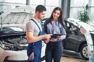 A man mechanic and woman customer discussing repairs done to her vehicle photo