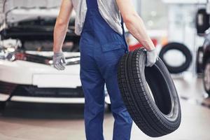 Mechanic holding a tire tire at the repair garage. replacement of winter and summer tires photo