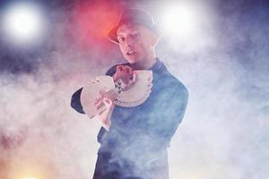 Magician showing trick with playing cards. Magic or dexterity, circus, gambling. Prestidigitator in dark room with fog photo