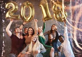 un grupo de jóvenes alegres tienen números que indican la llegada de un nuevo año 2018. la fiesta está dedicada a la celebración del año nuevo. conceptos sobre el estilo de vida de la unión juvenil foto