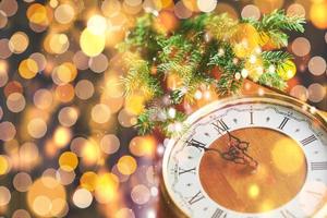 feliz año nuevo a la medianoche de 2018, viejo reloj de madera con luces navideñas y ramas de abeto foto