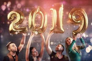 A group of merry young people hold numbers indicating the arrival of a new 2019 year. The party is dedicated to the celebration of the new year. Concepts about youth togetherness lifestyle photo
