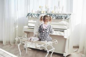 Two happy little girls in pajamas play the piano on Christmas day photo