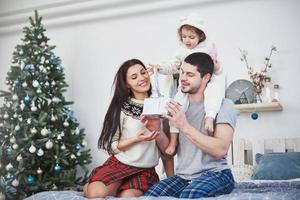 Happy family at christmas in morning opening gifts together near the fir tree. The concept of family happiness and well-being photo