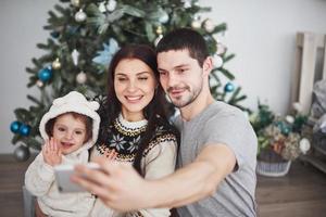 Family gathered around a Christmas tree, using a tablet photo