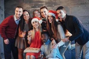 el nuevo año está llegando. Grupo de alegres jóvenes multiétnicos con gorro de Papá Noel en la fiesta, posando concepto de gente de estilo de vida emocional foto