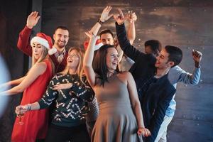 fiesta con amigos. aman la navidad. grupo de jóvenes alegres que llevan bengalas y copas de champán bailando en la fiesta de año nuevo y mirando felices. conceptos sobre el estilo de vida de la unión foto