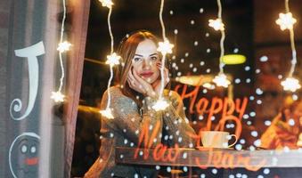 Young beautiful woman sitting in cafe, drinking coffee. Model listening to music. Christmas, Happy new year, Valentines day, winter holidays concept photo