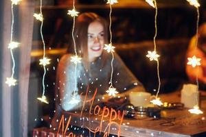 hermosa mujer joven sentada en la cafetería, bebiendo café. navidad, feliz año nuevo, día de san valentín, concepto de vacaciones de invierno foto