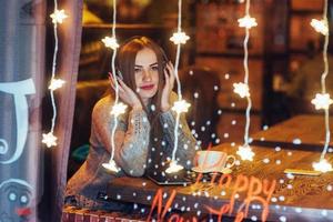 hermosa mujer joven sentada en la cafetería, bebiendo café. modelo escuchando música. navidad, año nuevo, día de san valentín, concepto de vacaciones de invierno foto