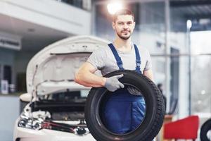 Mechanic holding a tire tire at the repair garage. replacement of winter and summer tires photo