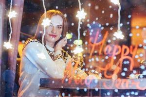 hermosa mujer joven sentada en la cafetería, bebiendo café. navidad, feliz año nuevo, día de san valentín, concepto de vacaciones de invierno foto