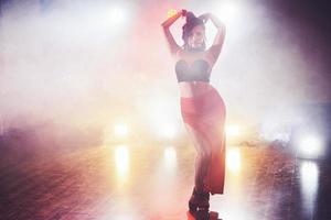 Skillful and beautiful dancer girl performing in the dark room under the concert light and smoke, performing an artistic and emotional contemporary dance photo