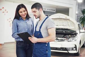 un hombre mecánico y una mujer cliente discutiendo las reparaciones hechas a su vehículo foto