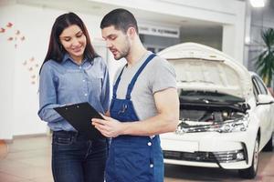 A man mechanic and woman customer discussing repairs done to her vehicle photo