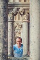 joven viajero mirando a la cámara y posando entre columnas de piedra del castillo medieval de leiria en portugal foto