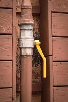 Yellow lever arm turned down on brown painted pipe and plank wall building photo