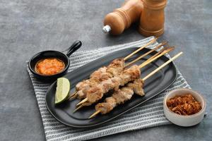 sate taichan, satay de pollo a la parrilla sin salsa de cacahuete ni salsa de soja. servido en un plato con salsa picante. foto