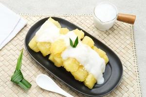 Singkong thailand, sweet cassava, made of boiled cassava, sugar and coconut milk. Served in black plate and pandan leaf photo