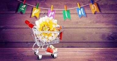 Mini shopping cart with colorful flowers and butterflies. photo