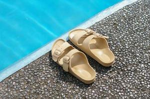 A pair of plastic sandals by side of swimming pool photo