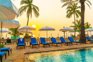 palm tree with umbrella chair pool in luxury hotel resort at sunrise times photo
