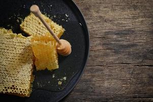 cucharón de panal y miel sobre mesa de madera foto