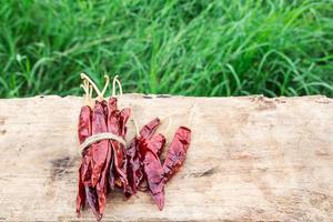 Dried chili peppers on wooden with green grass background