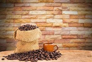 Coffee beans in burlap sack on wooden table with blurred background