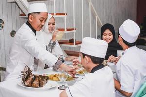feliz familia musulmana asiática celebrando eid mubarak comiendo juntos en el comedor foto