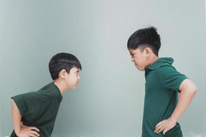 Two angry siblings looking each other on grey background photo