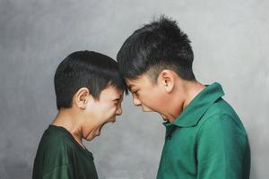 Two angry boys shouting to each other on grey background photo