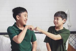 Two happy siblings giving fist bump at bedroom photo