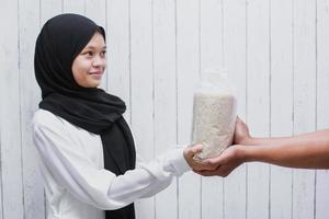 joven musulmana dando arroz para zakat fitrah como obligación en el mes sagrado del ramadán foto