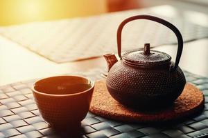 té chino en tetera de arcilla y taza vacía en la mesa foto