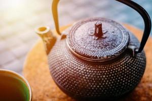 Green tea in teapot and cup closeup photo