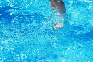 Piernas bajo el agua en el primer plano de la piscina azul foto