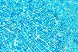 superficie de agua ondulada en la piscina con reflejo del sol foto
