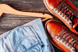 casual leather brown shoes, jeans and hanger on dark background photo