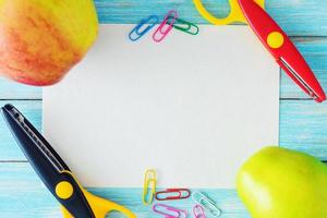 blank paper sheet, two apples and scissors on blue background, top view photo