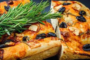 Traditional Italian Focaccia with olives, garlic and rosemary, homemade bread photo