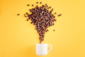 Coffee cup with beans on yellow background photo