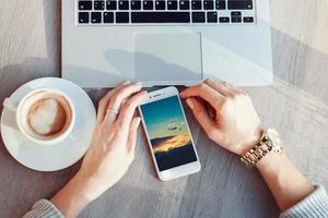 woman using smartphone and laptop in cafe. Young girl drinks coffee and works photo