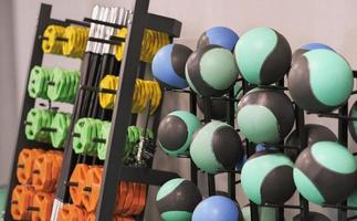 sport gym equipment, balls and barbells on a wall holder. gym or fitness center, wellness and healthy lifestyle photo